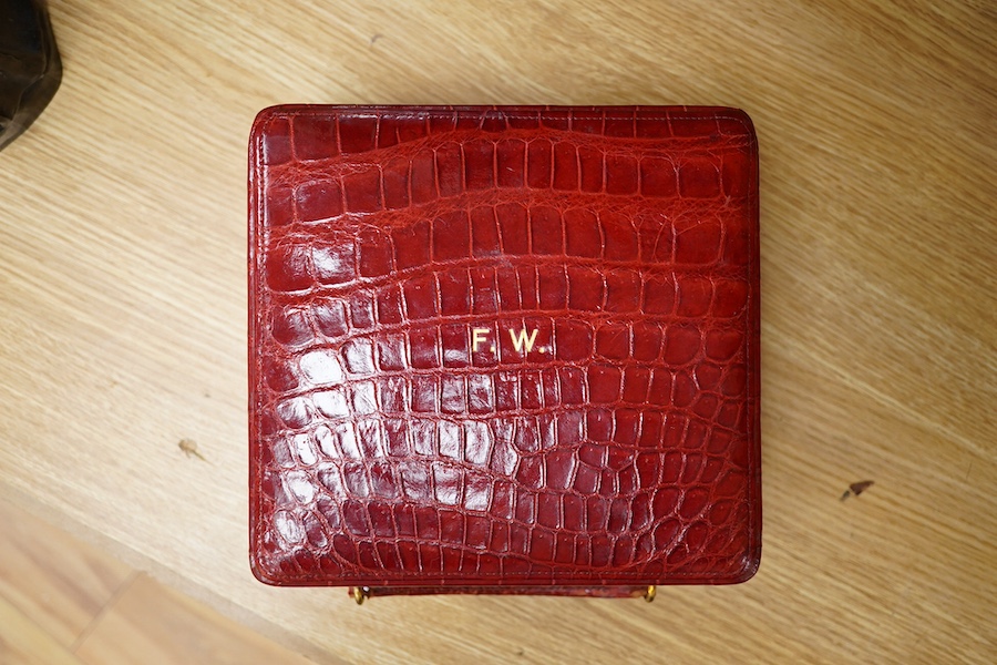 A red stained crocodile skin two layer vanity case, fitted with brass topped bottles and pots, case 22cm wide x 13.5cm high. Condition - handle has pulled away one side and needs re stitching